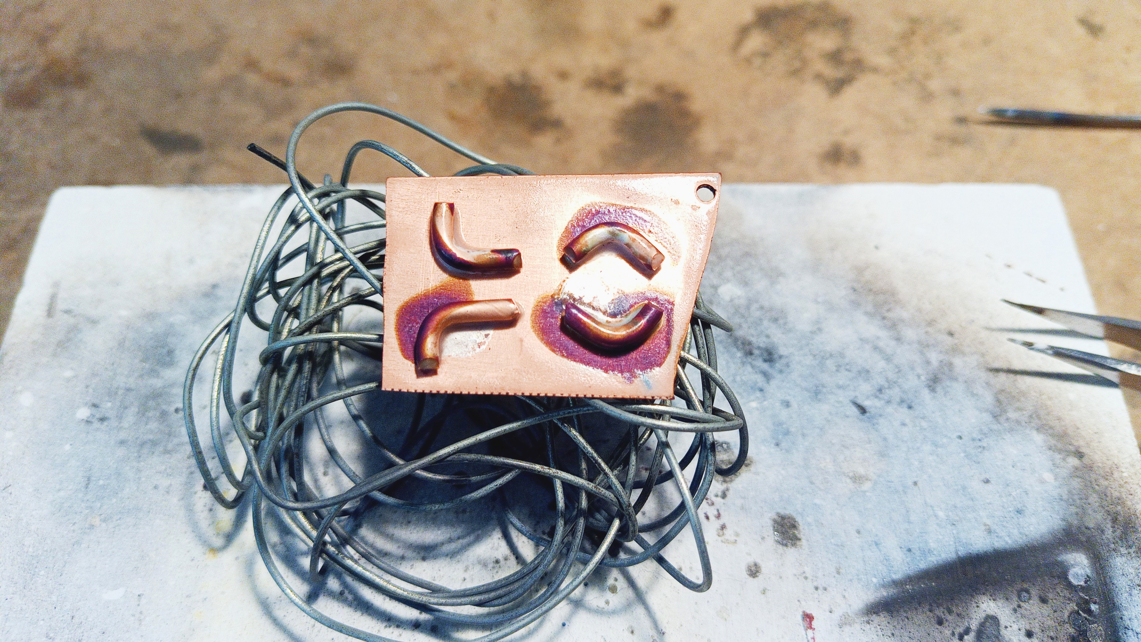 Four pieces of copper wire soldered onto a copper plate
